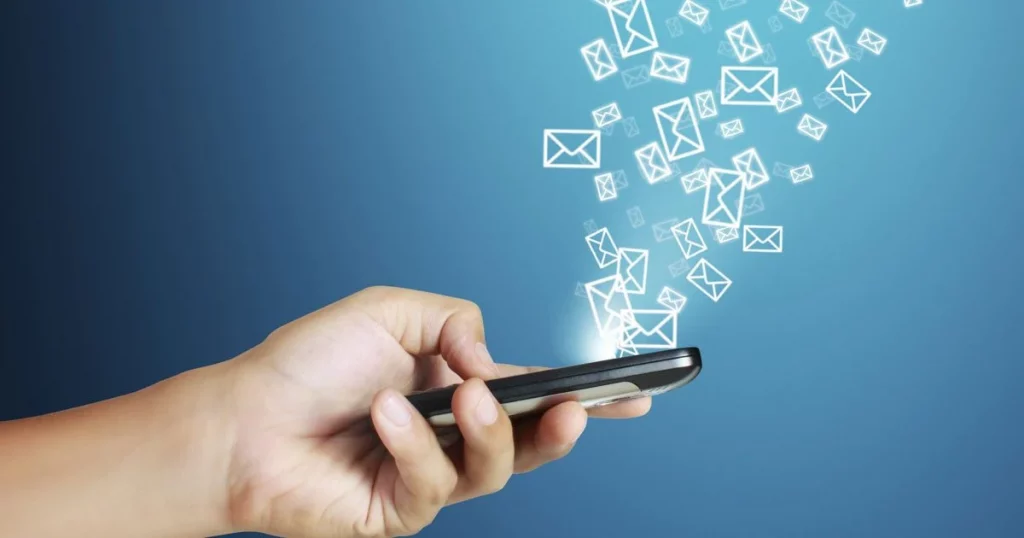 personne tenant dans sa main un smartphone avec des logos d'emails sur fond bleu