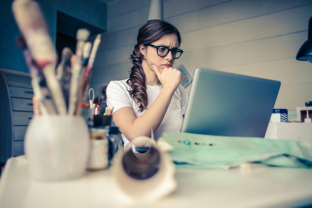 Femme portant des lunettes assise à un bureau avec un ordinateur portable devant elle.