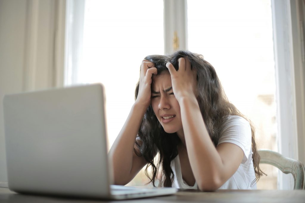 Une femme assise à une table, la tête dans les mains, exprimant un moment de stress.
