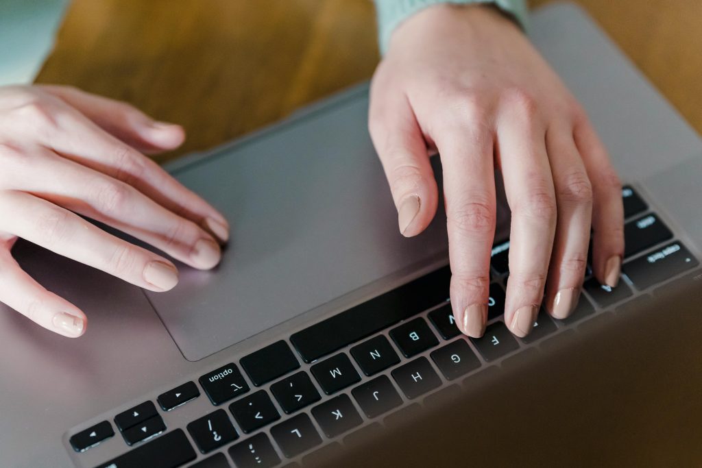 Un individu utilisant un ordinateur portable, les doigts posés sur le clavier, absorbé par son activité.