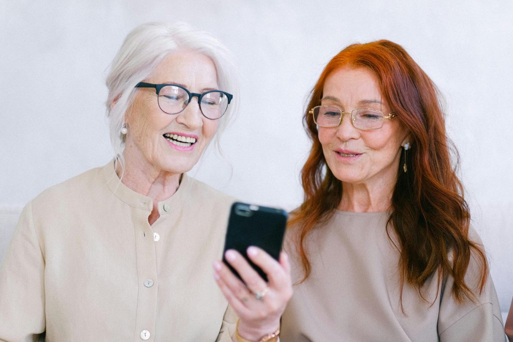 Deux femmes seniors observant un téléphone mobile avec attention.